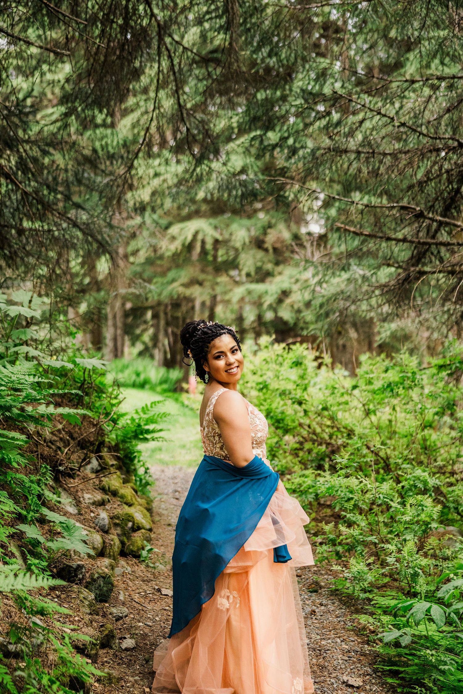 Wedding portrait on a forest path with lush greenery and ferns in the background.