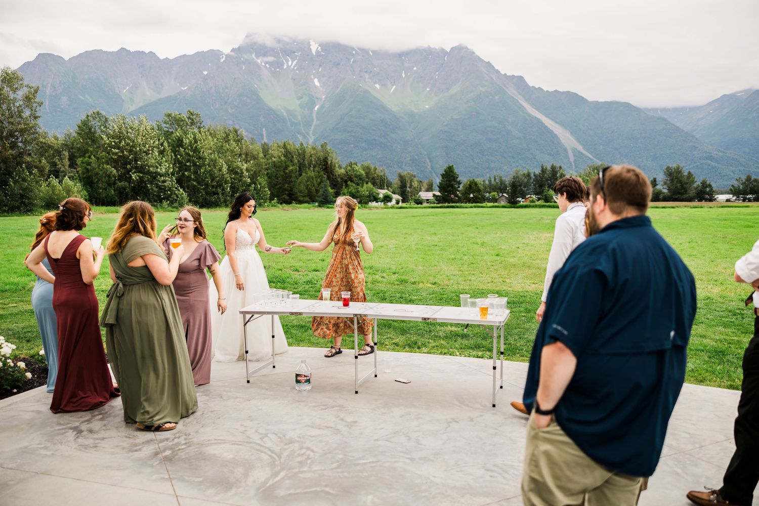 Wedding party in colorful dresses poses for photos with mountain backdrop.