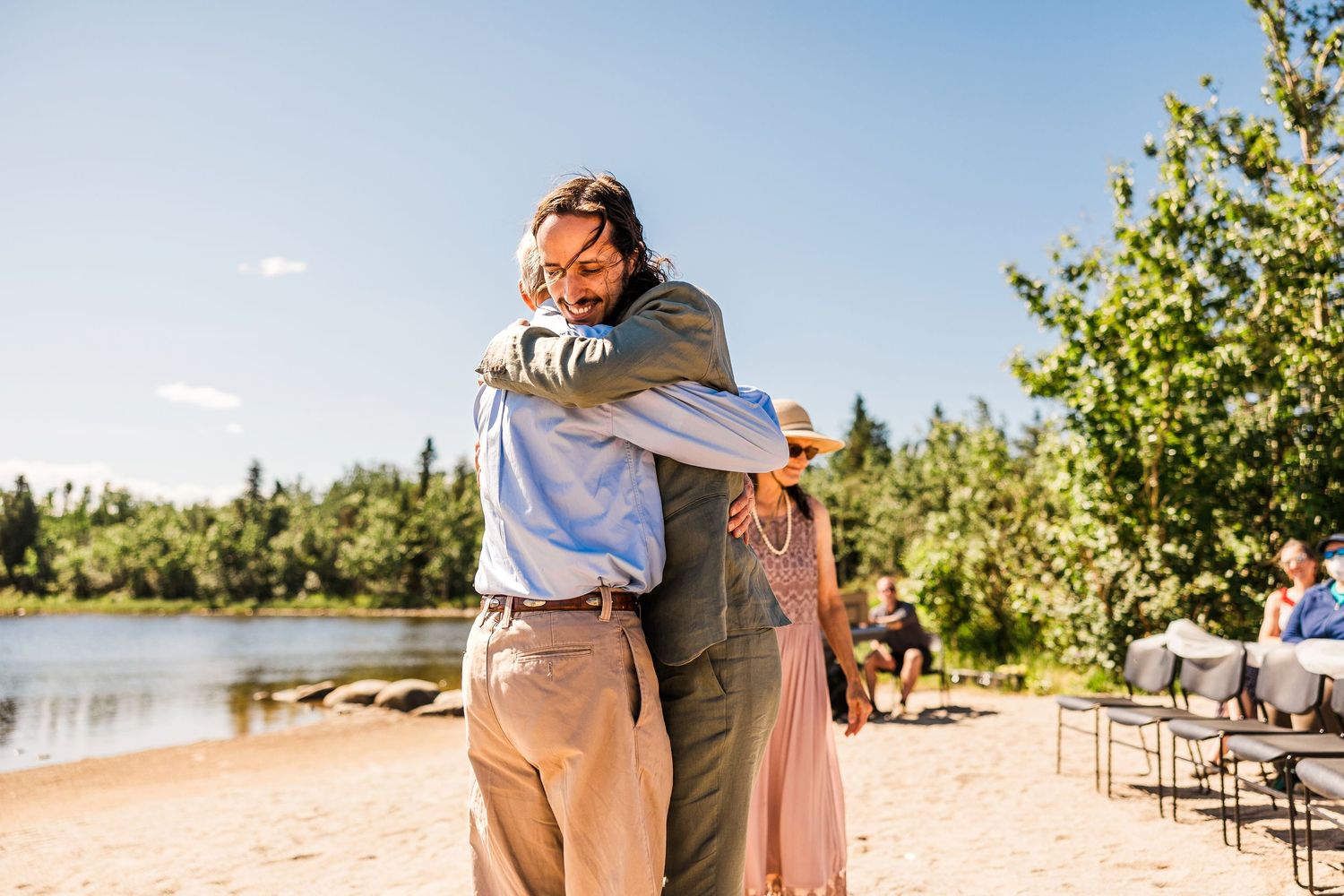 Wedding couple shares first dance on beach with guests watching in background.