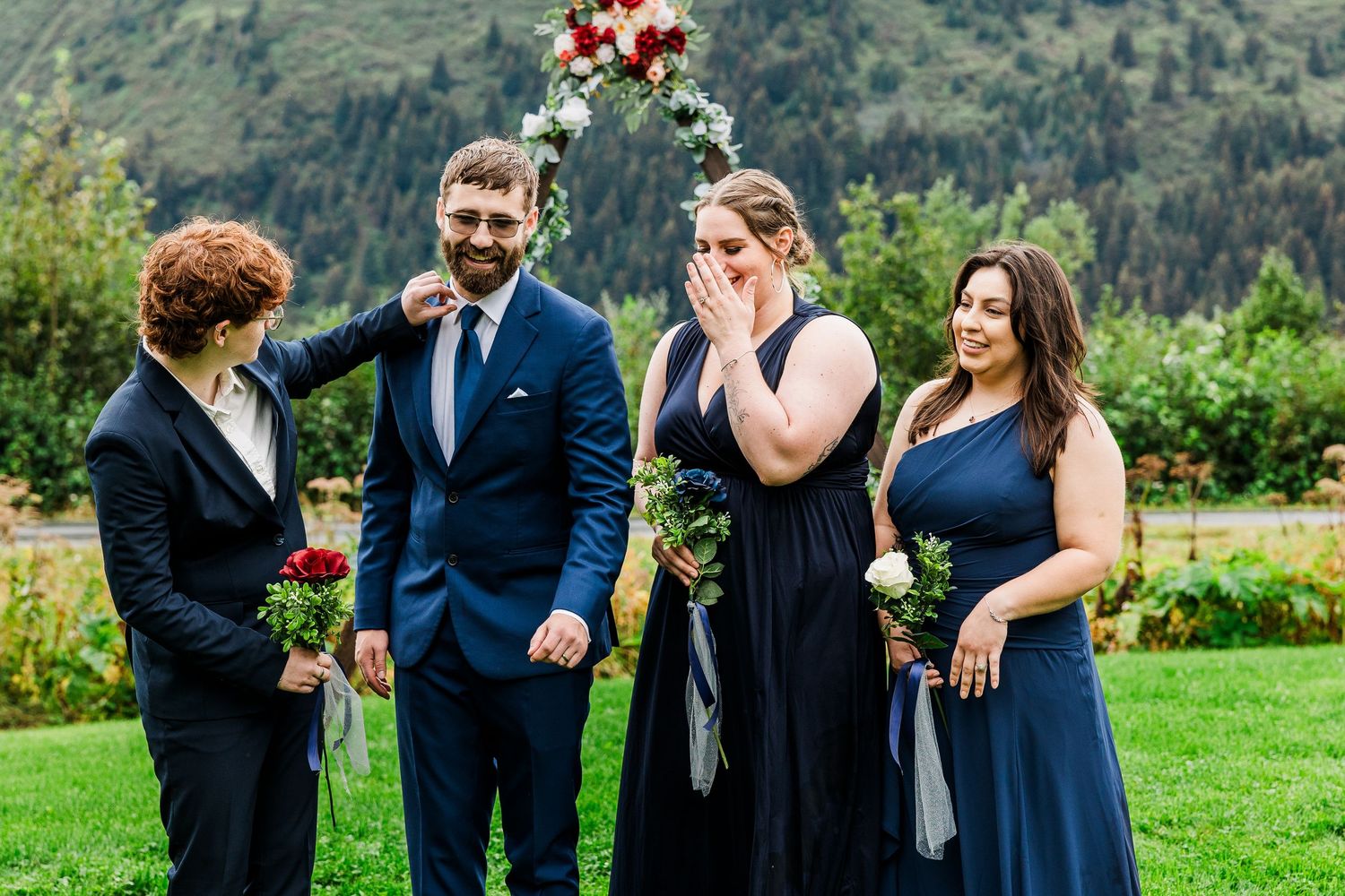 Wedding party members share a laugh together on mountain meadow.
