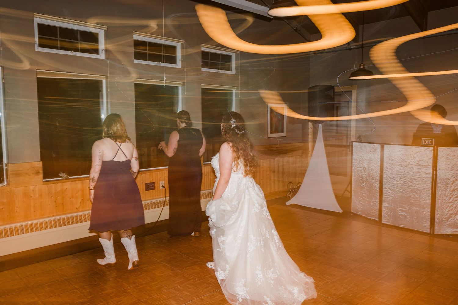 A bride in a white gown dances in a reception hall with ambient lighting.