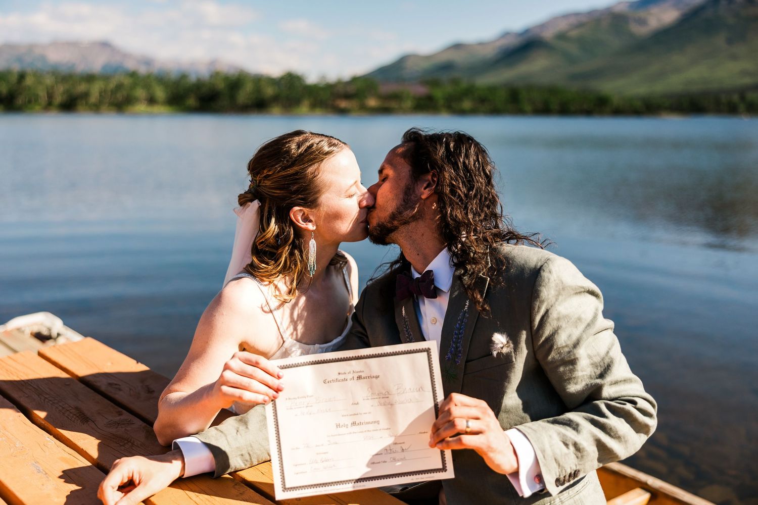 Romantic moment while holding marriage certificate by mountain lake.