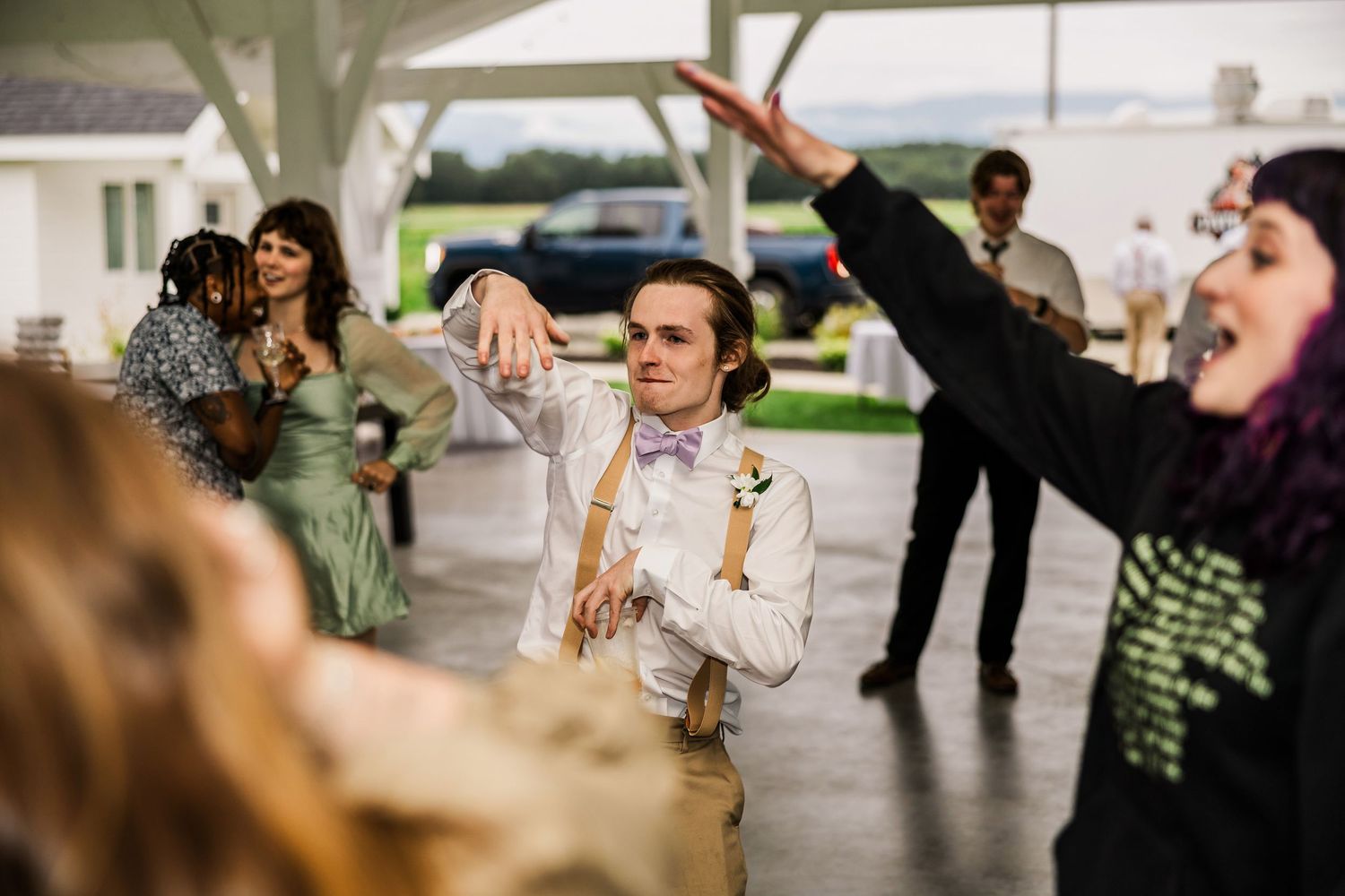 Wedding guests dancing and celebrating enthusiastically at an indoor reception venue.