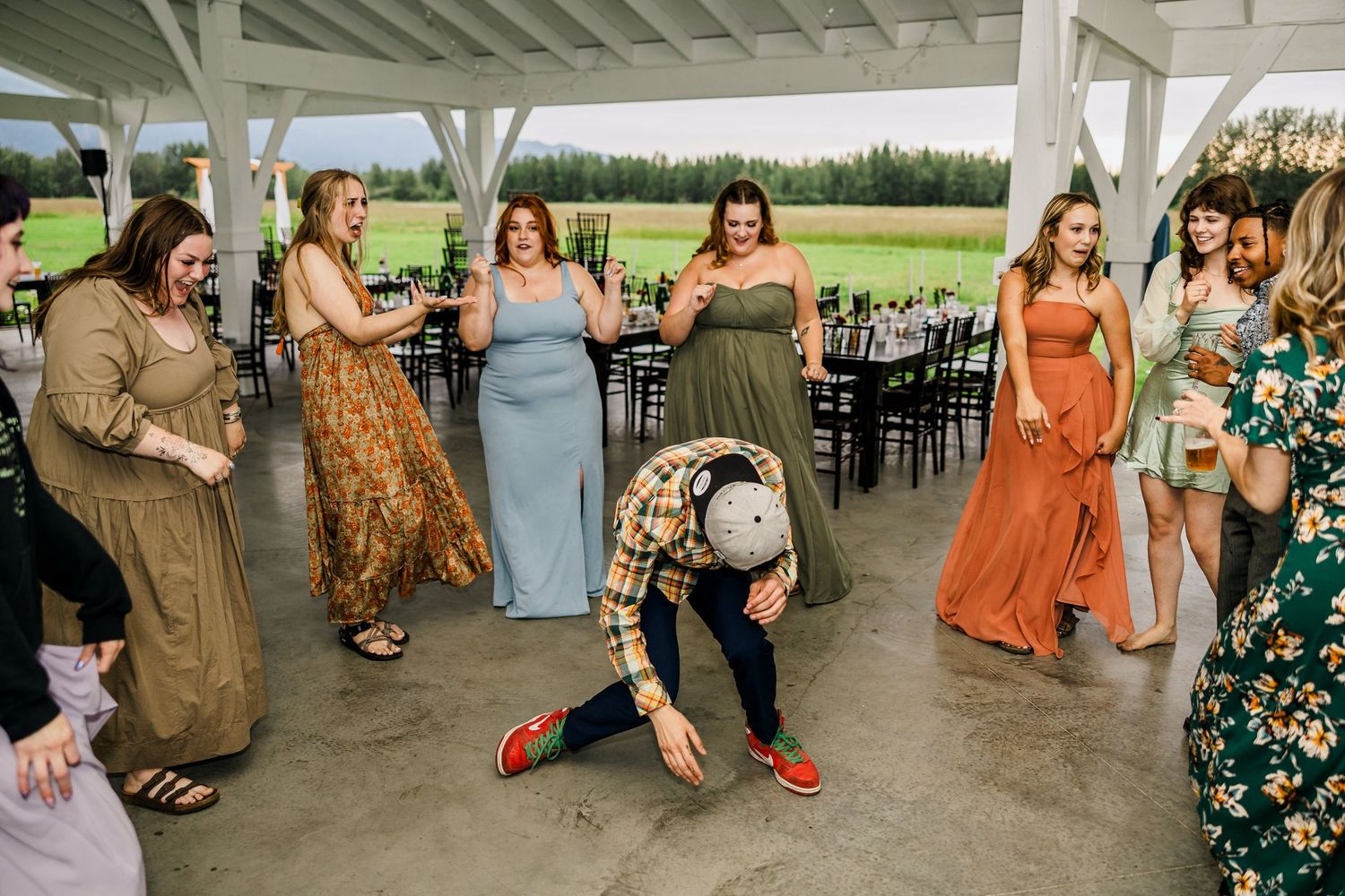Group of wedding guests dancing and having fun at an outdoor covered venue.
