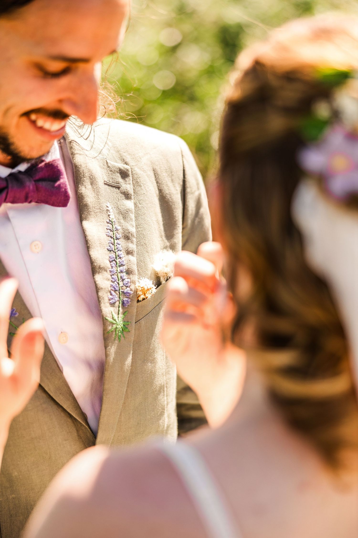 Close-up of groom's boutonniere and beige suit jacket with pink bowtie.
