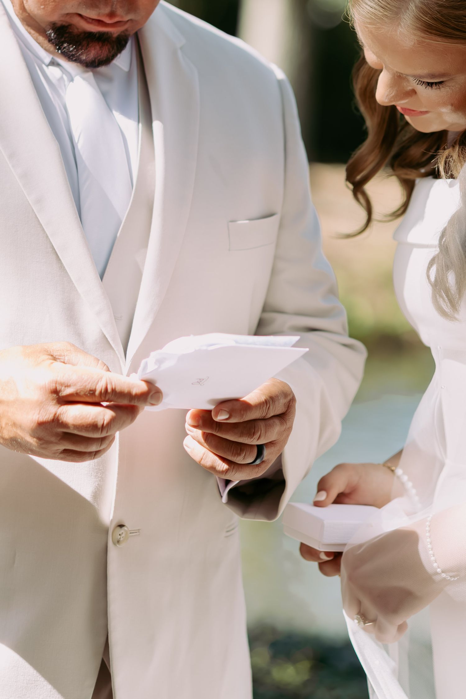 Officiant and bride exchange notes during an intimate outdoor wedding ceremony in natural light.