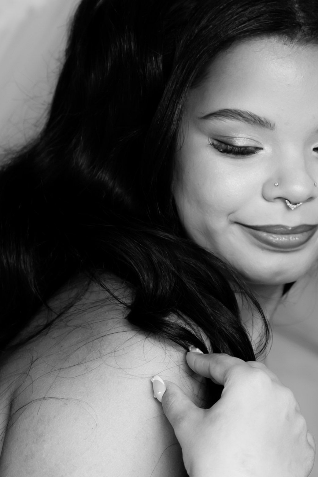 Black and white close-up of smiling bride with nose ring being buttoned into her wedding dress.