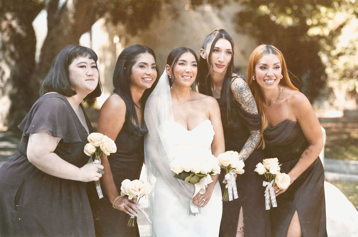 A bride laughing with her bridesmaids wearing dark chocolate dresses at a Monrovia Historical Museum wedding.