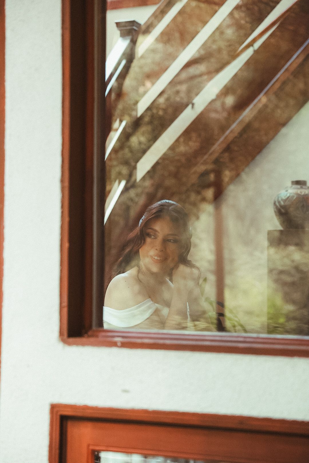 A candid reflection shot of a bride getting ready seen through a window at a Topanga Canyon wedding.