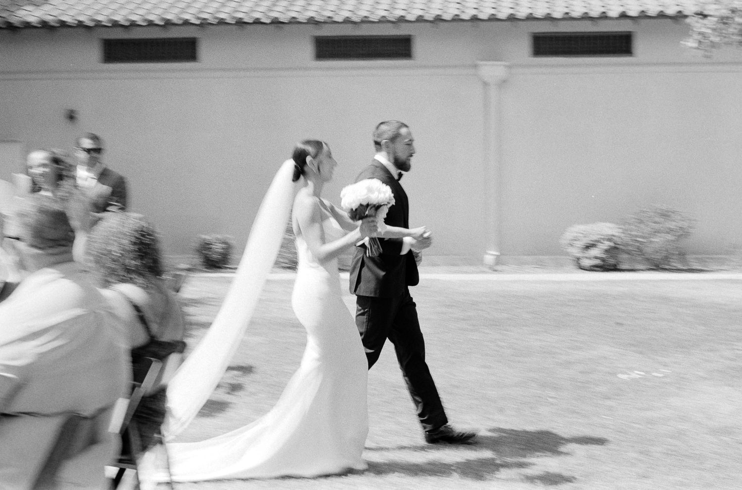 Blurry motion film photography of a bride and groom walking down the aisle after their ceremony at a Los Angeles wedding.