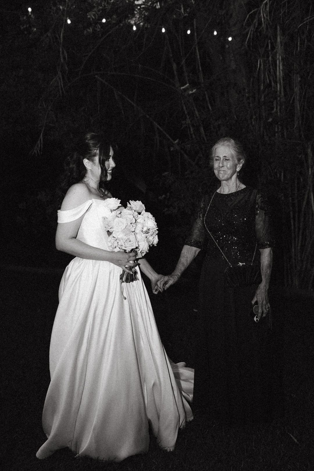 Black and white film photography of a bride holding hands with her grandmother at a Topanga wedding.