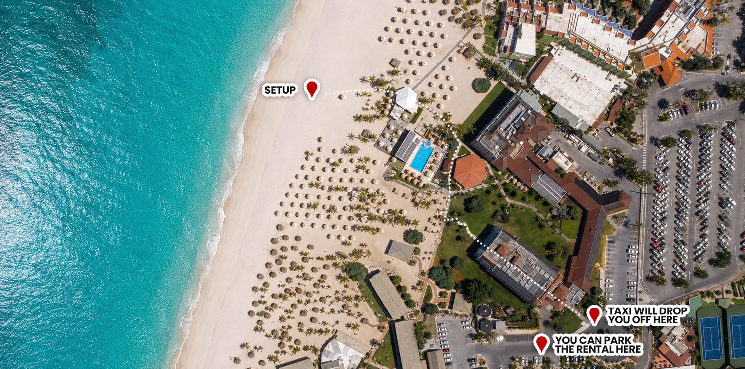 Aerial view of a luxury beachfront resort with turquoise waters, white sandy beach, pool, and parking area in a tropical location.