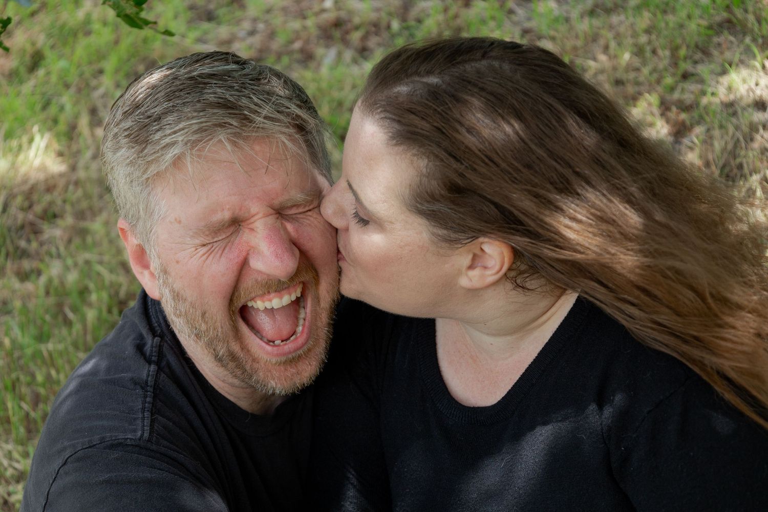 A joyous candid moment captured outdoors showing laughter and affection between two people.