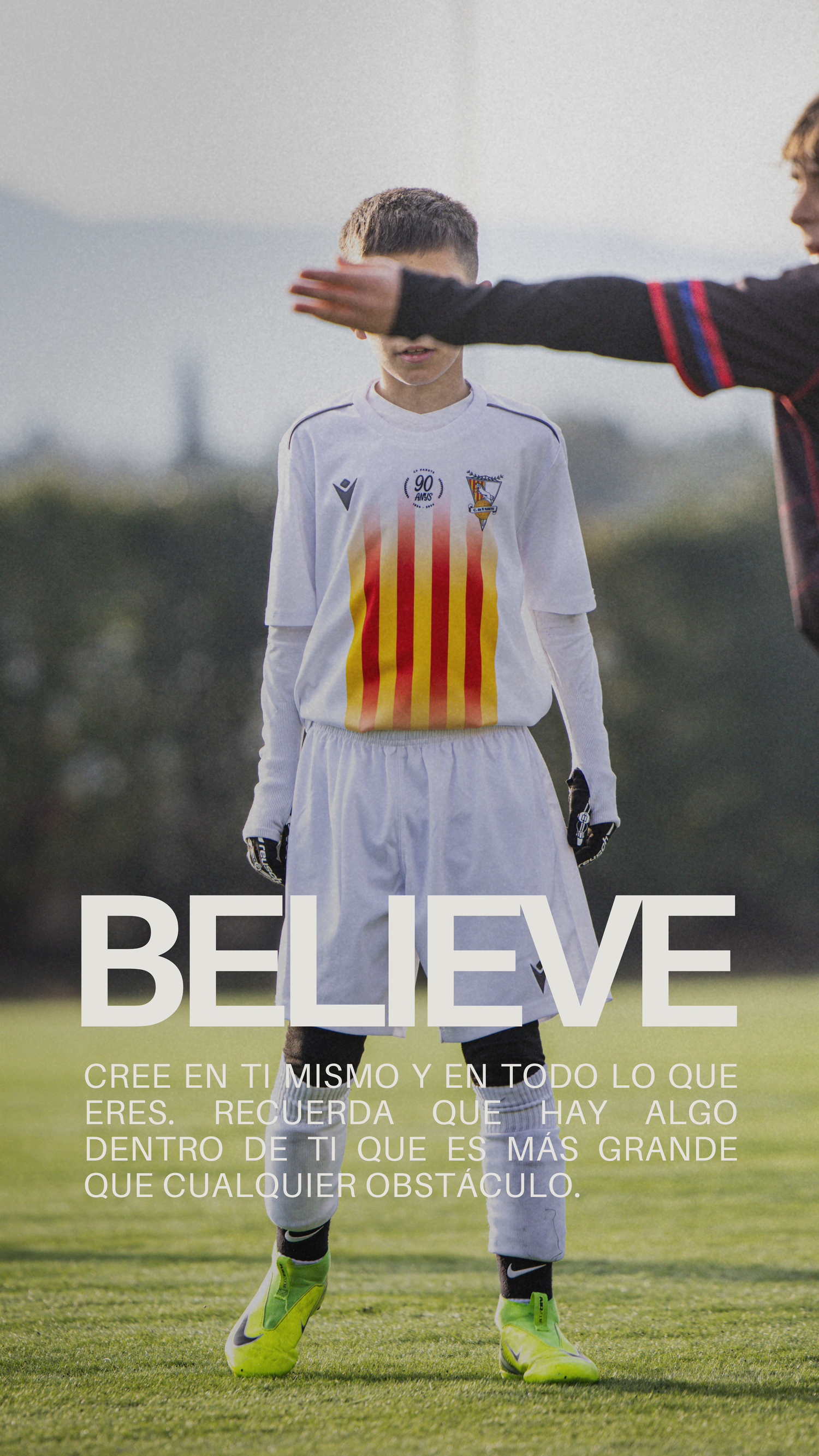Young soccer player in white kit with Catalan flag crest under motivational BELIEVE text overlay.