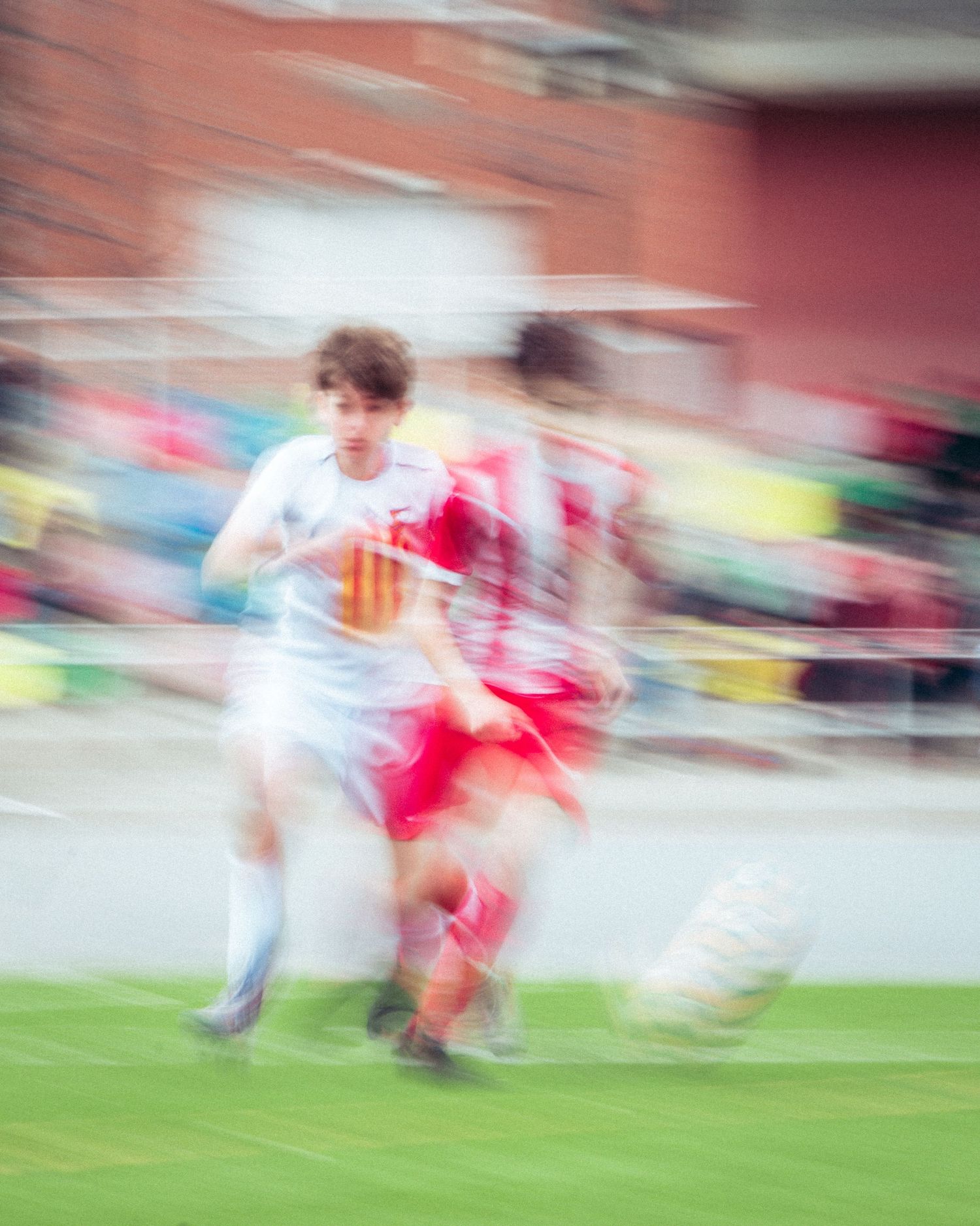 Motion blur action shot of two soccer players competing for ball in red and white kits.