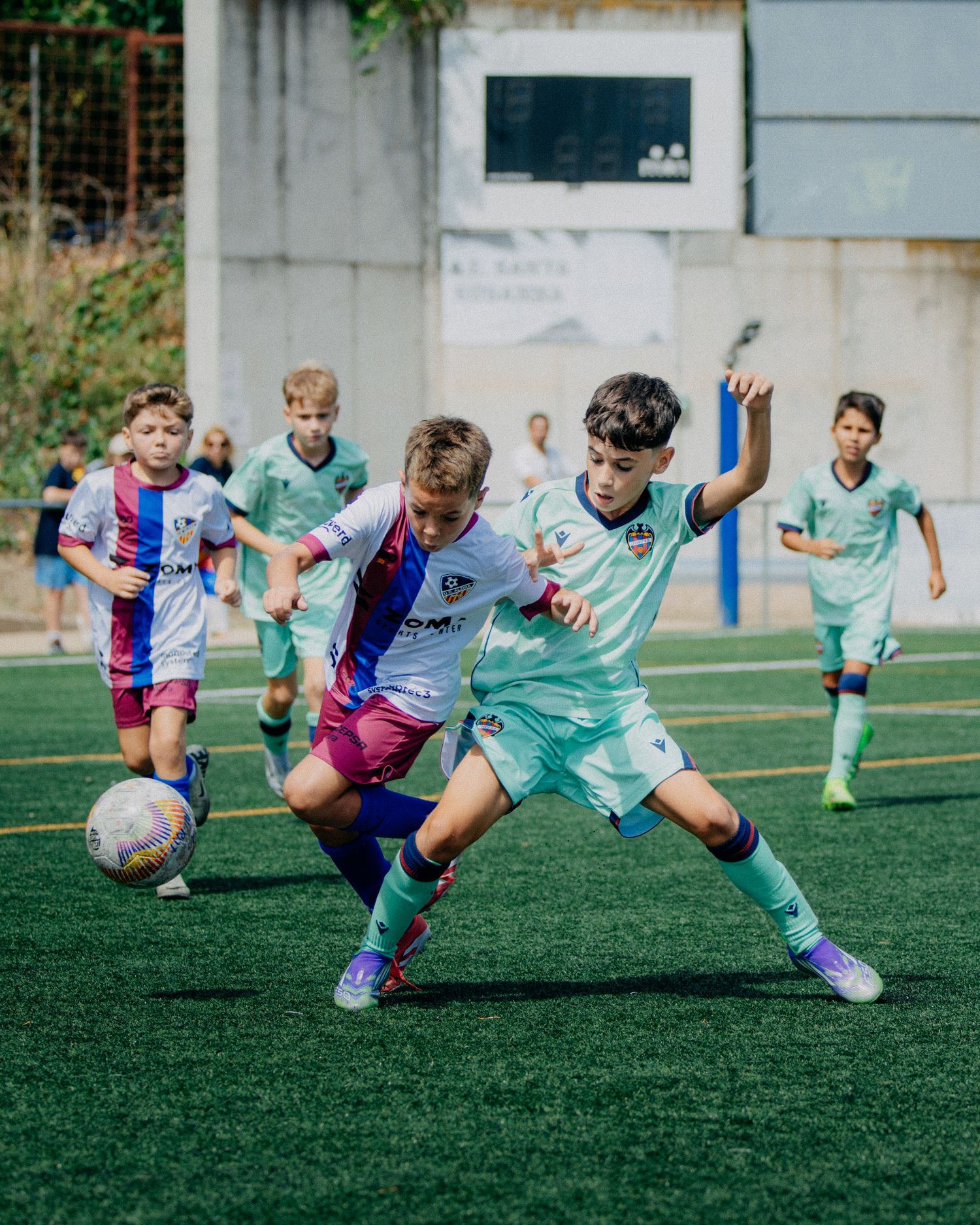 Young boys competing for the ball during a youth soccer match on an artificial turf field.