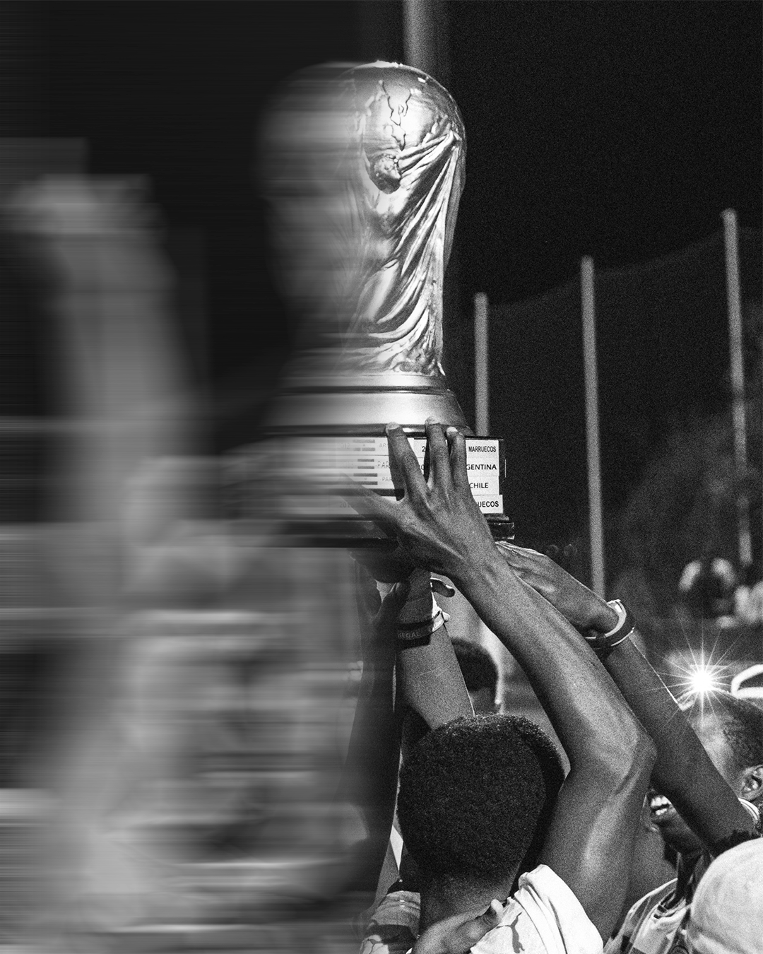 Black and white photo of players lifting a trophy above their heads in celebration.