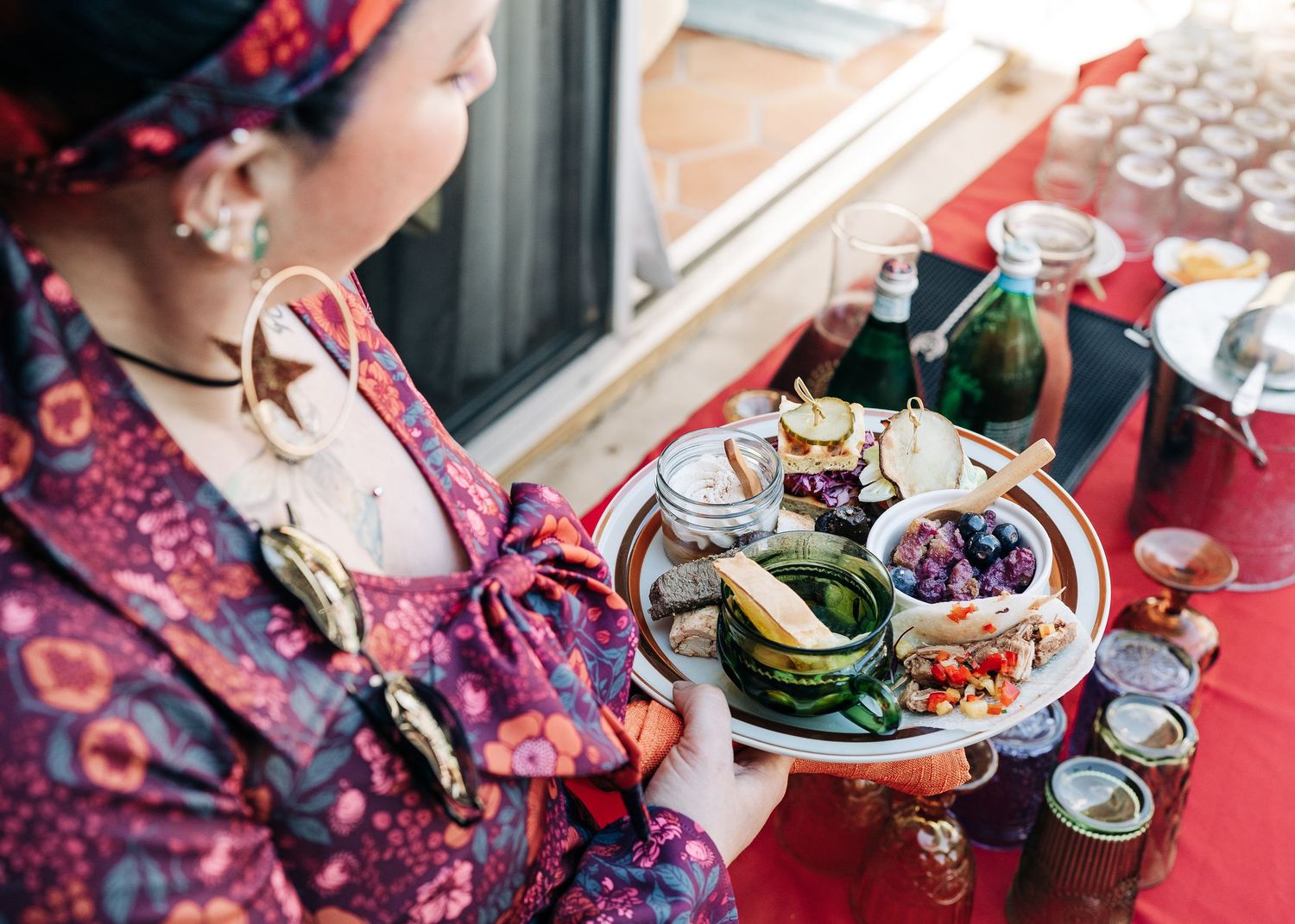 A colorful tablescape of afternoon tea service with teapots, snacks and treats arranged on a wooden surface.
