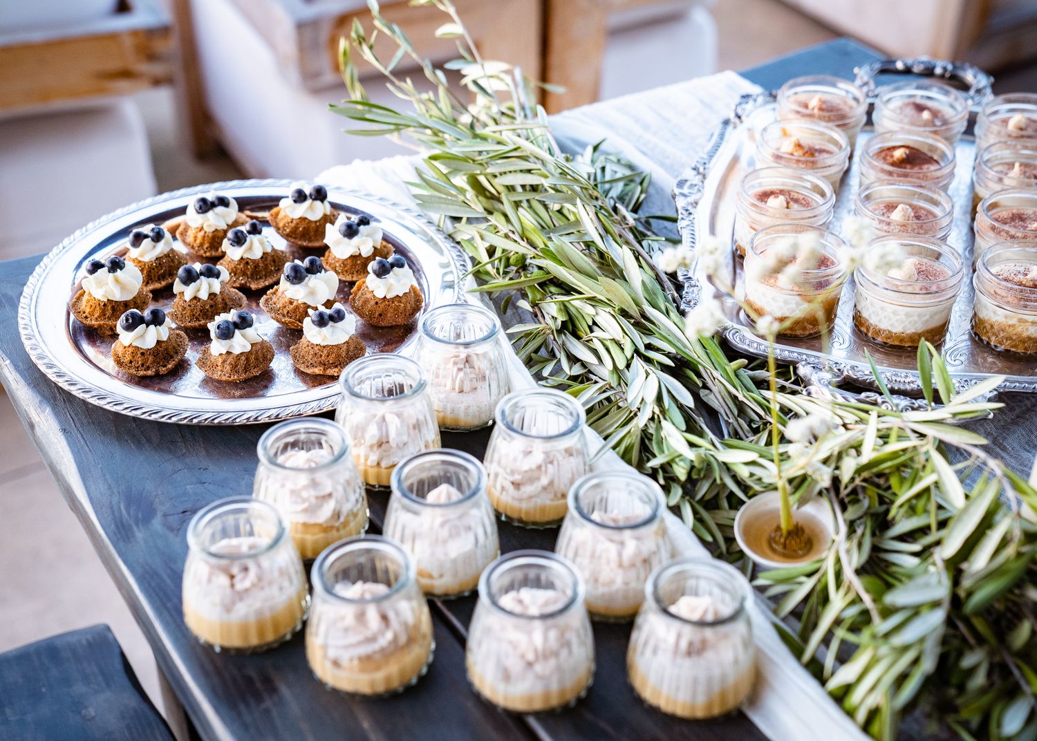 Elegant appetizer spread featuring mini desserts, canapes and garnished hors d'oeuvres on a buffet table.