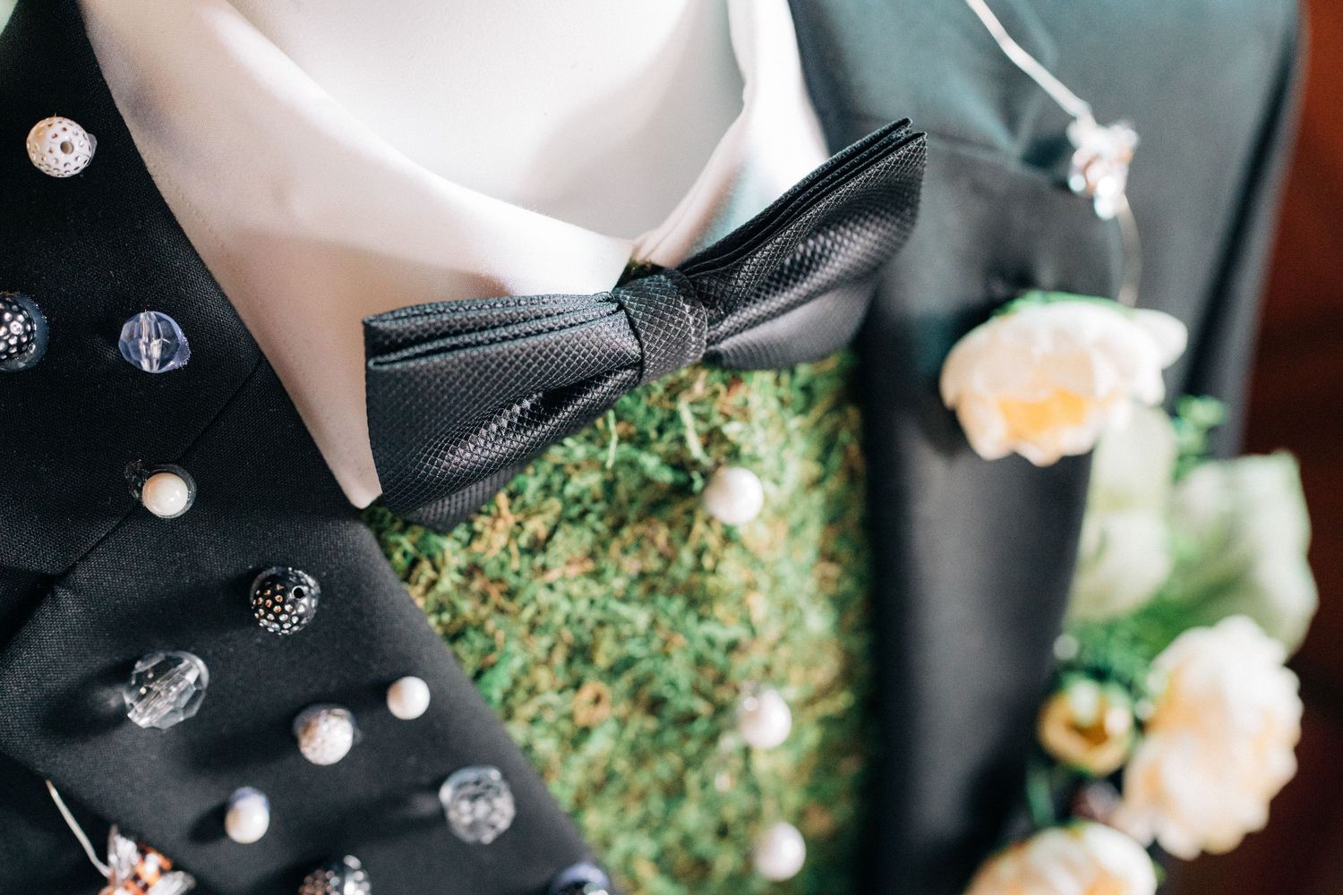 Elegant black bow tie and crystal embellishments on formal wedding attire.