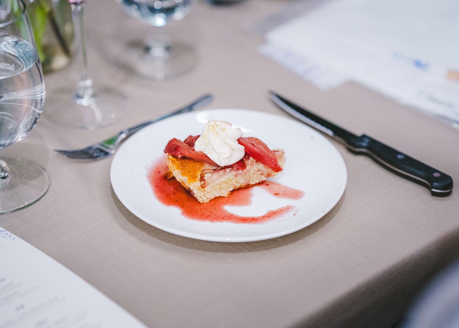 Pan-seared fish fillet with red sauce and yellow pepper garnish served on white plate with elegant table setting.