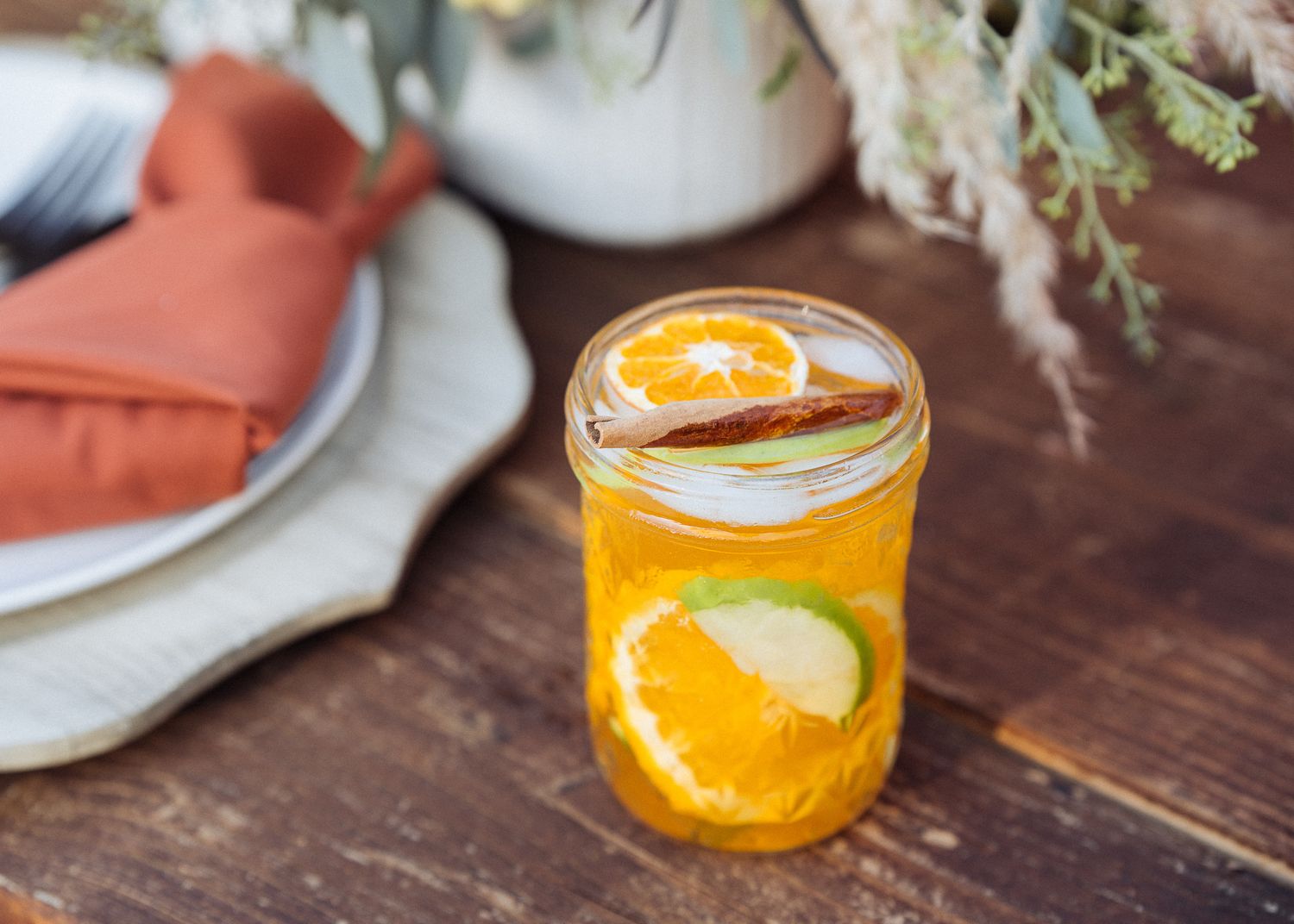 Refreshing citrus cocktail with orange slices and garnish in a glass mason jar on rustic wooden table.