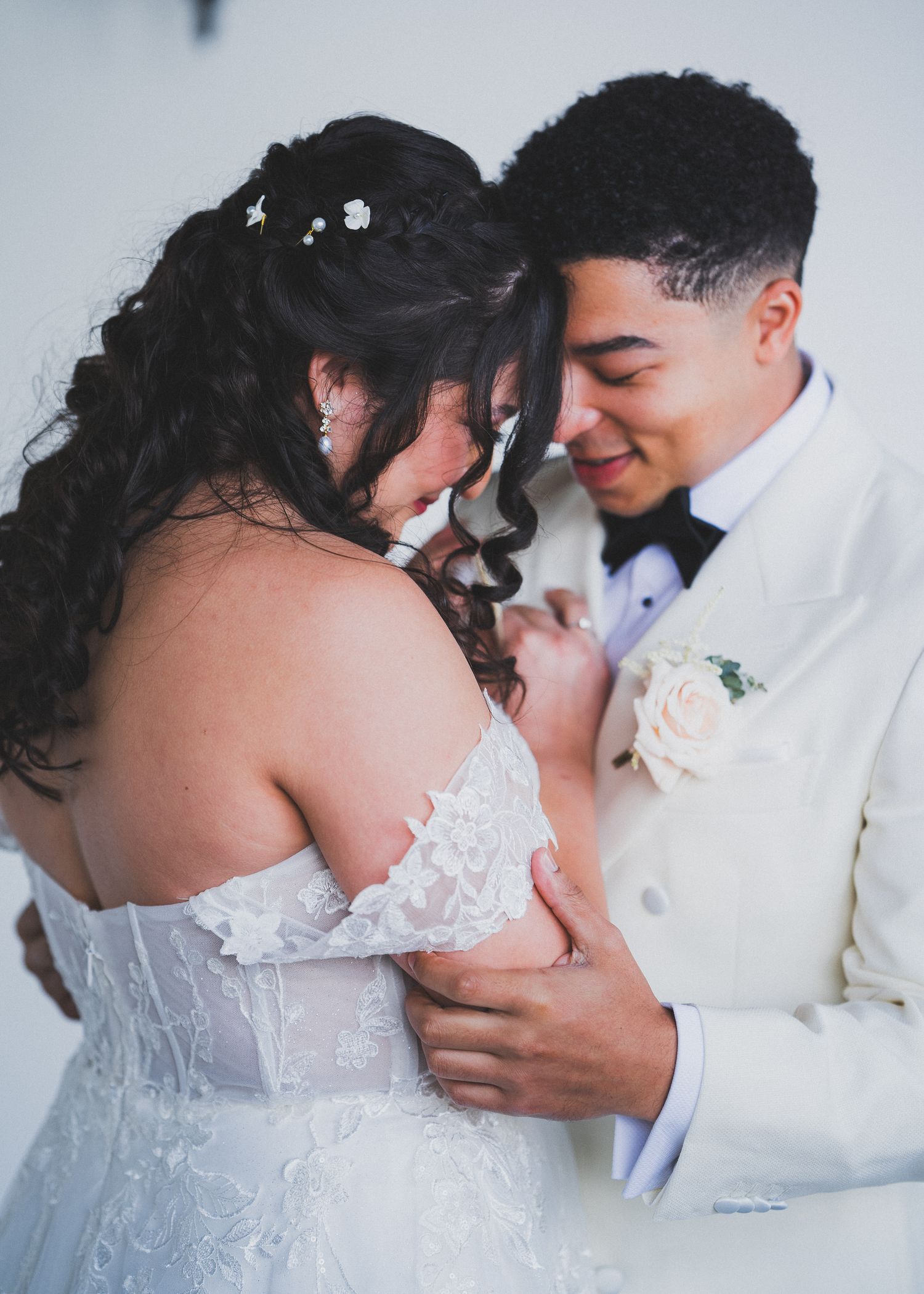Couple sharing a romantic moment in matching white outfits during a wedding photo session.