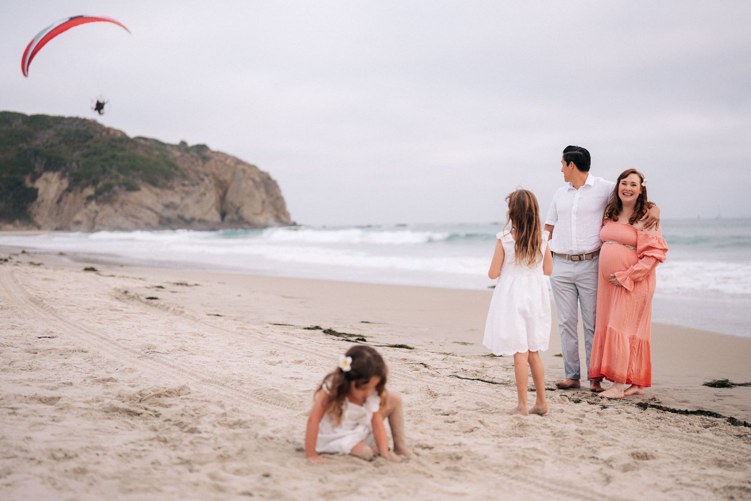 Family members holding hands while strolling along the shoreline of a misty beach.