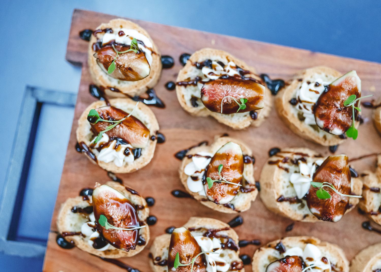Gourmet appetizers featuring bruschetta-style toppings and balsamic drizzle arranged on a wooden serving board.