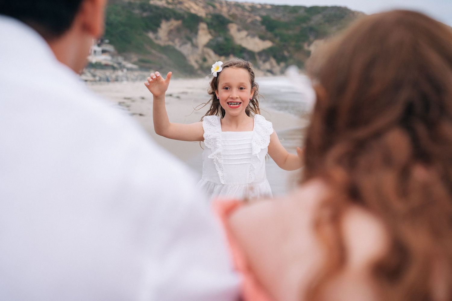 Family enjoying a candid moment together while walking on a scenic beach at sunset.
