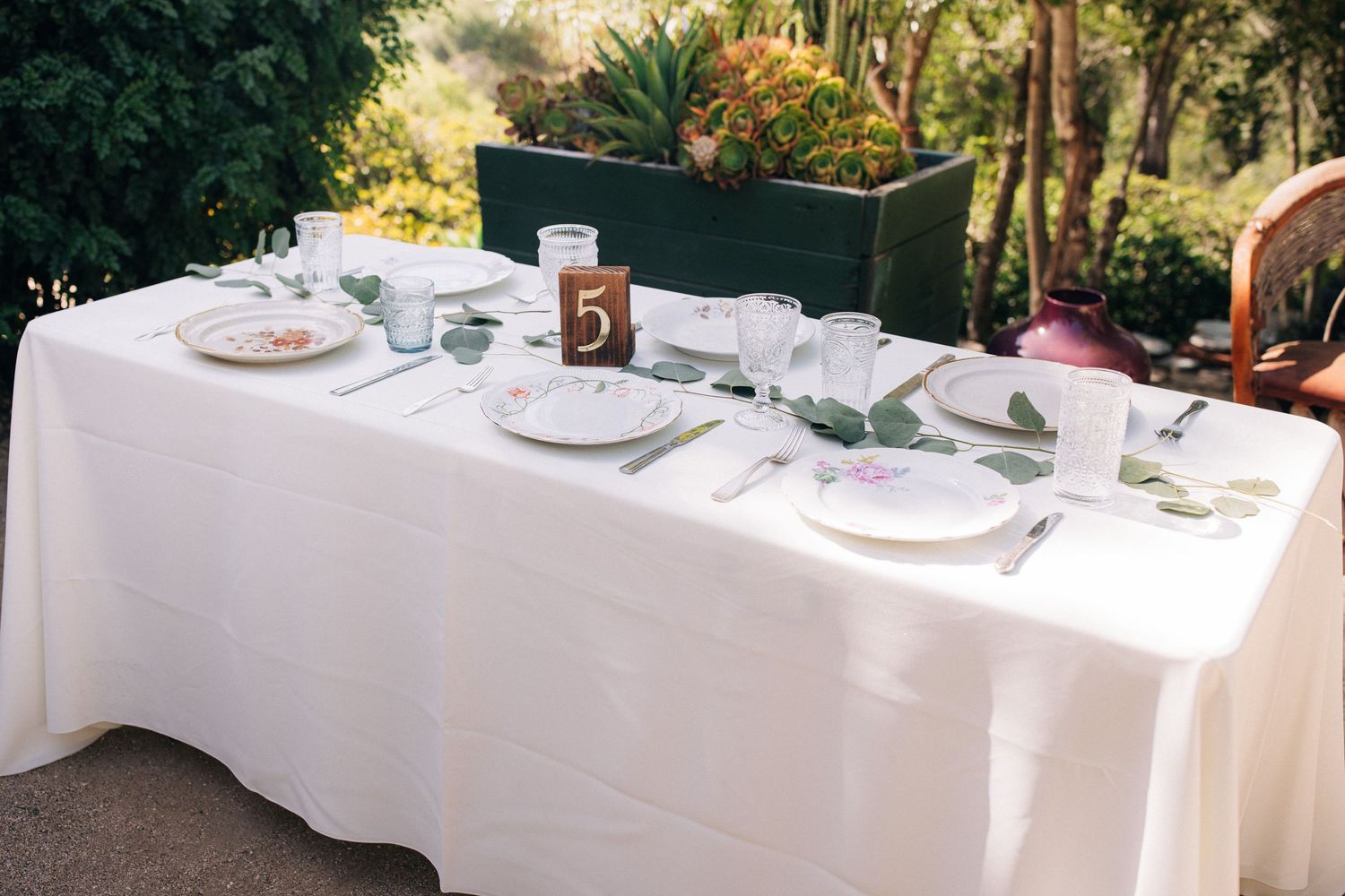 An elegant outdoor table setting with crisp white linens and formal place settings in a garden venue.
