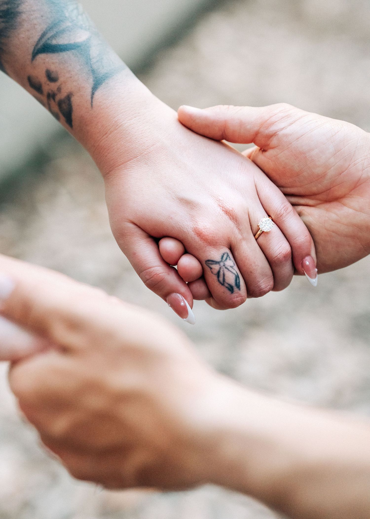 Two hands gently holding together with one showing a detailed geometric fox tattoo ring on their finger.