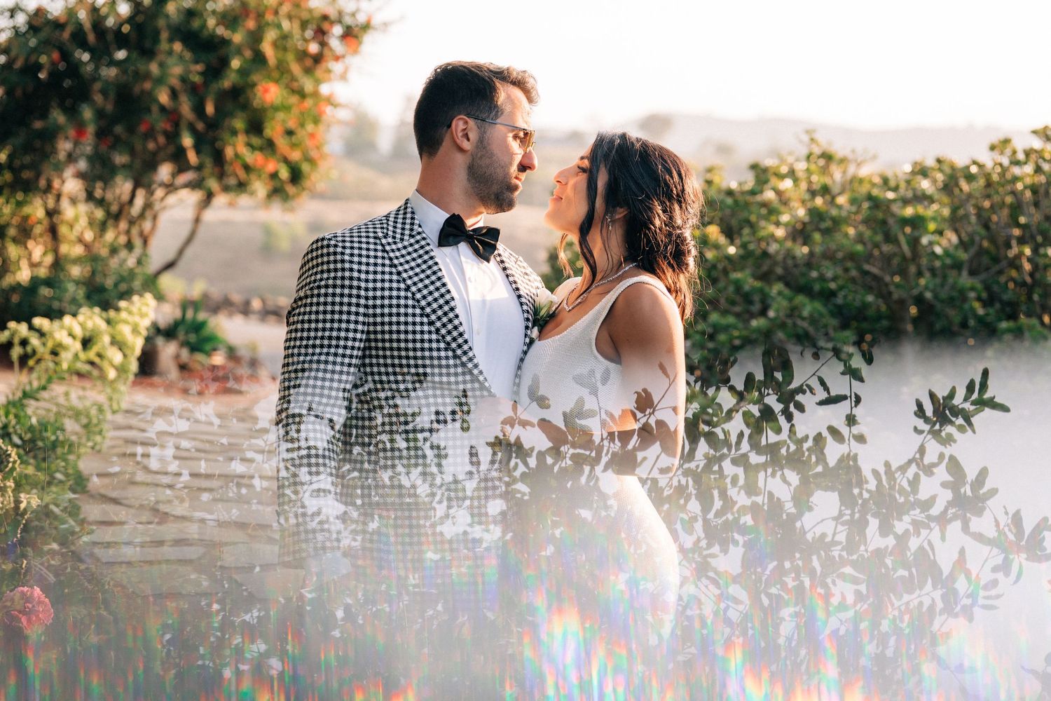 A romantic portrait of newlyweds sharing an intimate moment in a garden setting at sunset.