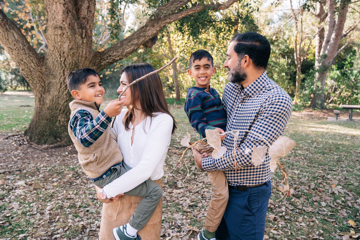 Group in casual attire playfully interacts while enjoying a sunny day in a park setting.