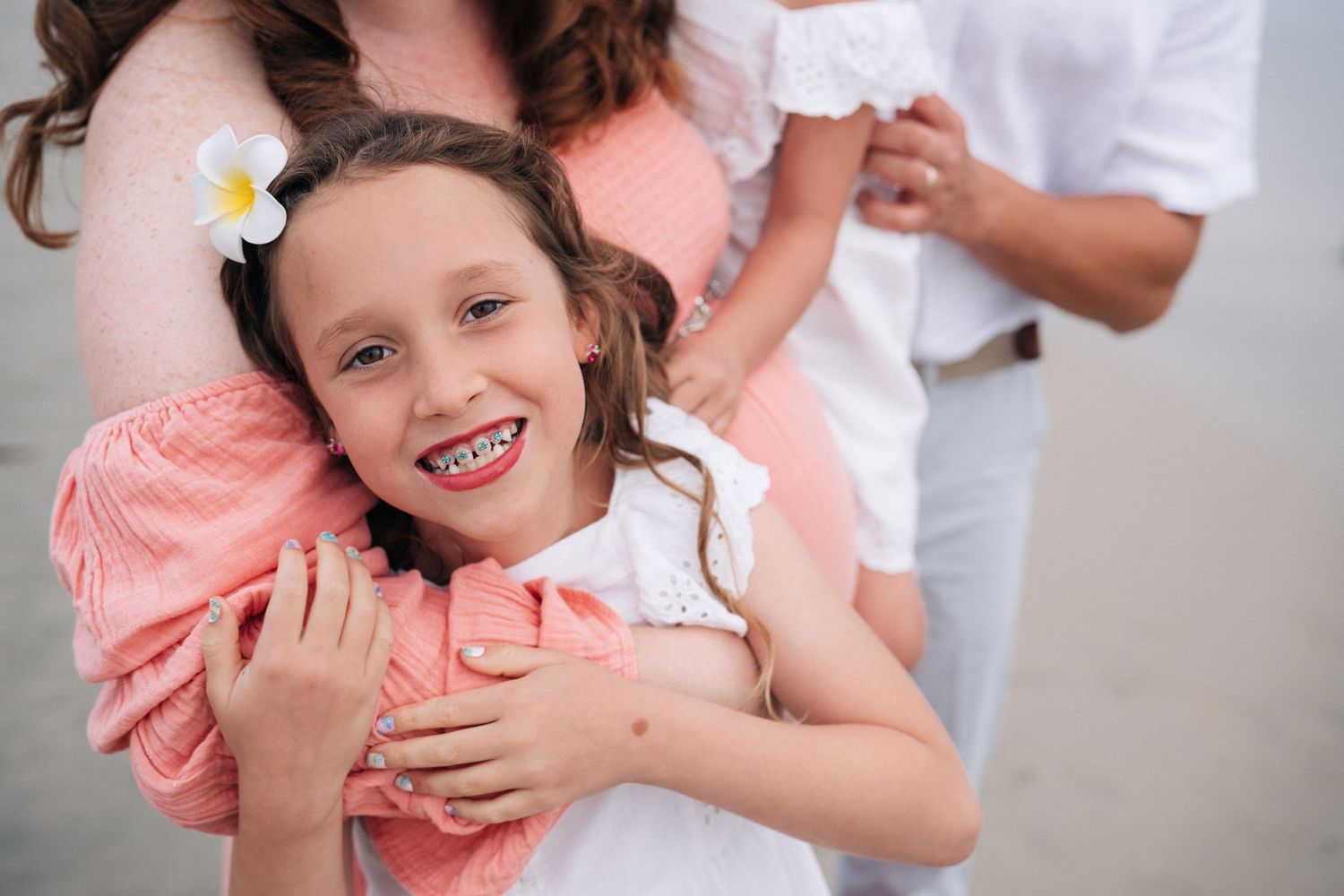 Multiple tender family moments captured in soft pink and white tones during an outdoor photo session.