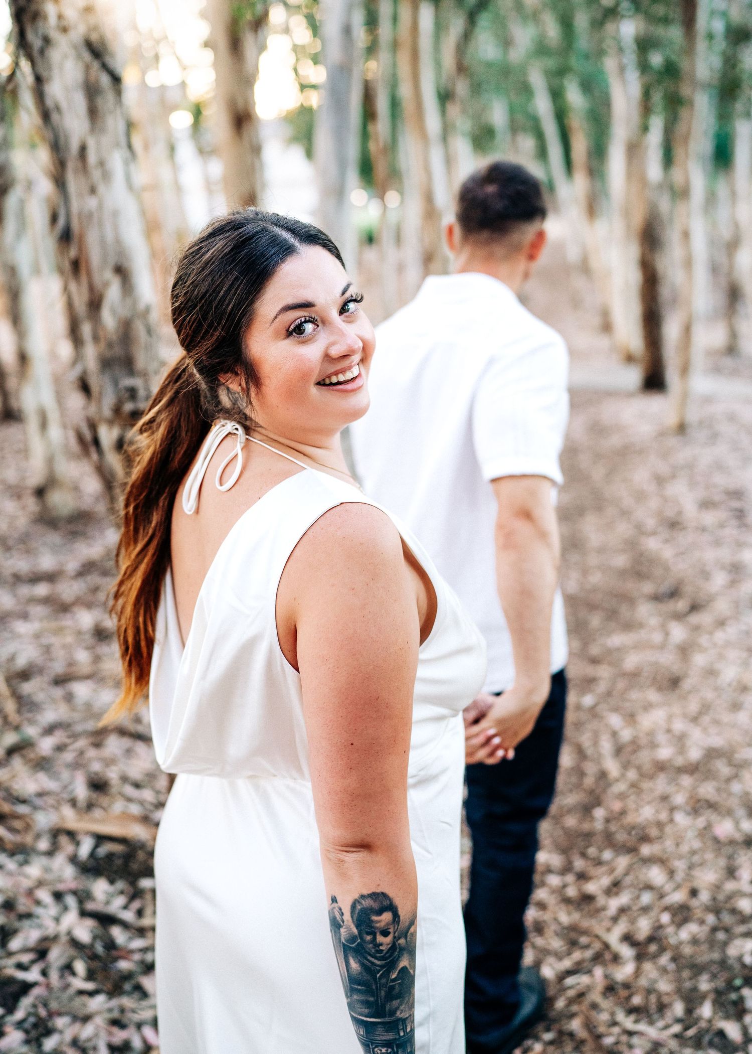 A couple shares a romantic moment walking along a eucalyptus forest trail surrounded by natural light.