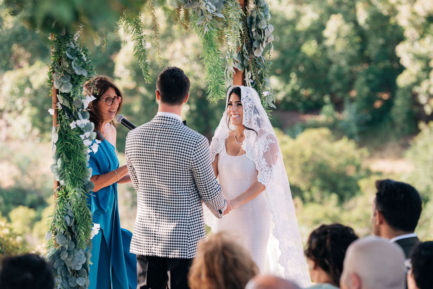 Garden wedding ceremony with guests gathered under floral arch.
