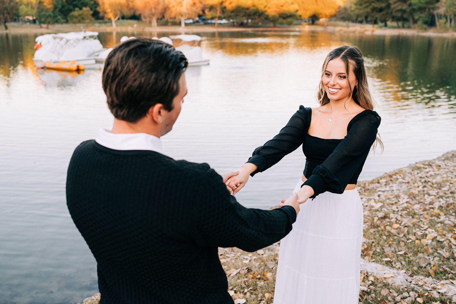 Two people share an intimate moment by a lake shore with soft lighting.