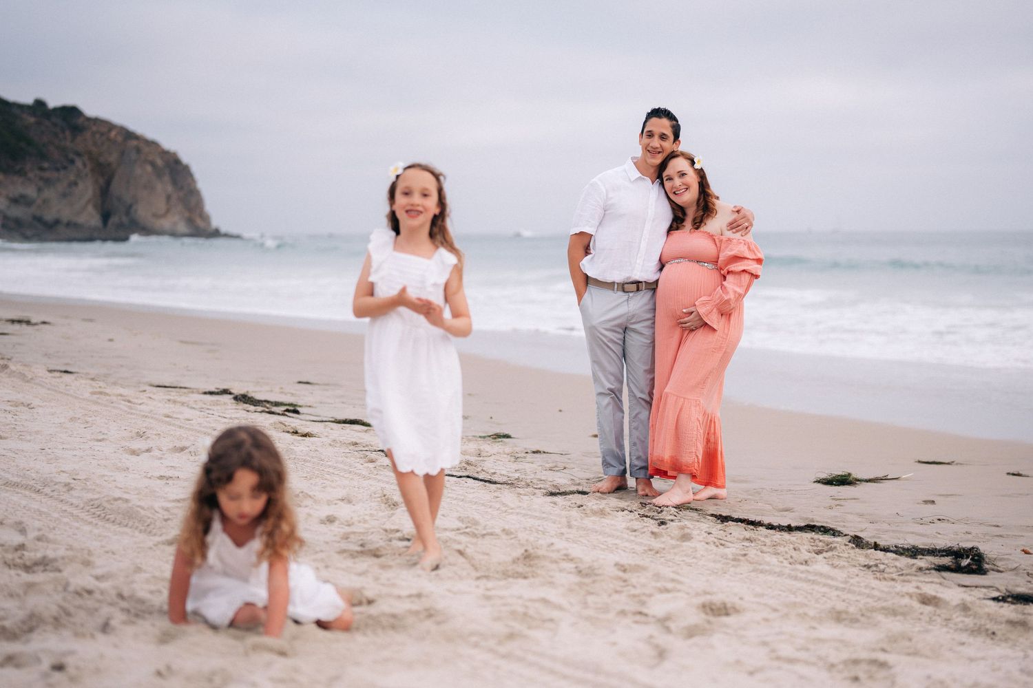 Group walking together on a foggy California beach with coastal cliffs in the background.