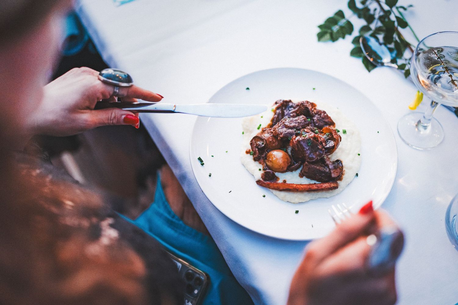 Elegant plated chocolate dessert being eaten at restaurant table with blue tablecloth.