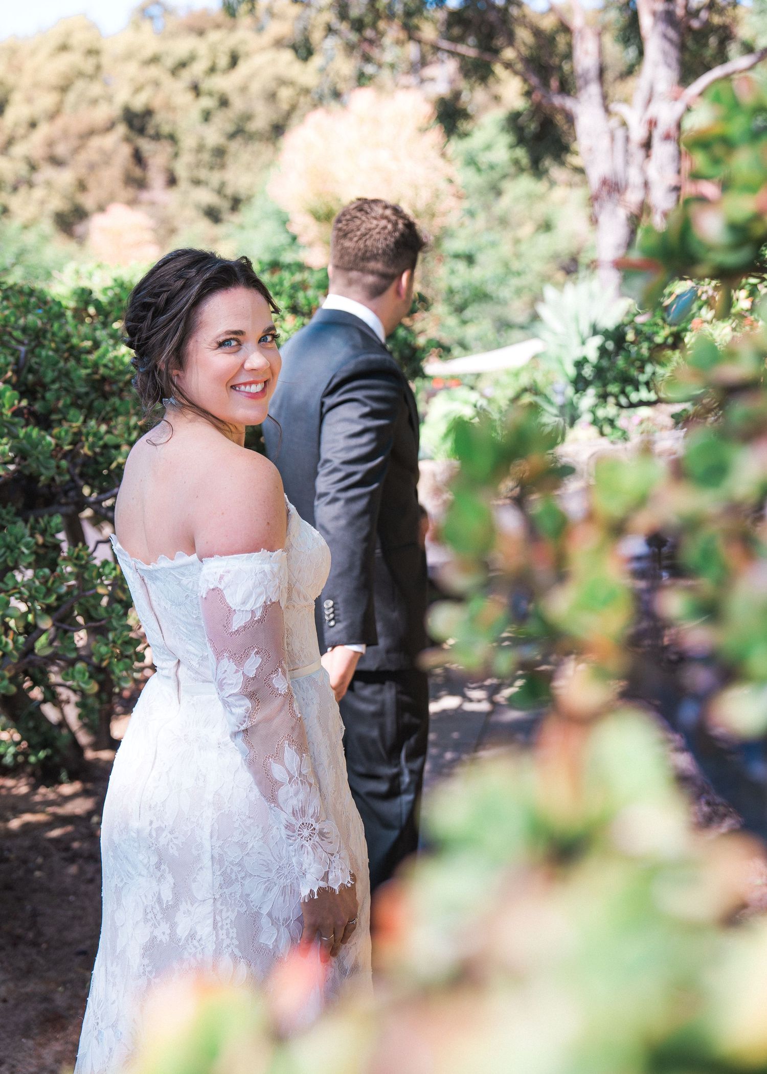 Wedding photography capture of a couple amidst lush garden foliage on their special day.