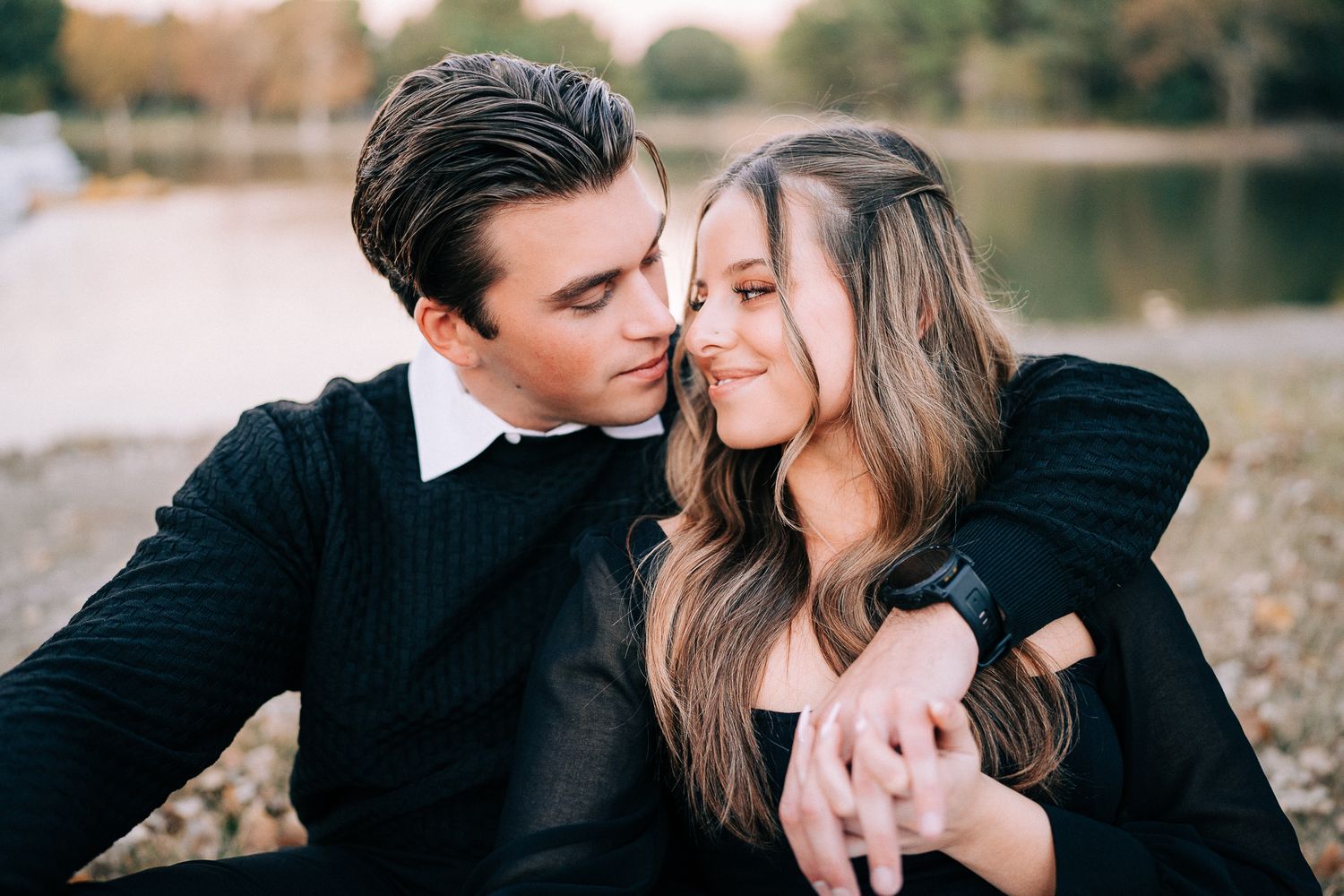 A romantic lakeside moment captured between two people in formal attire.