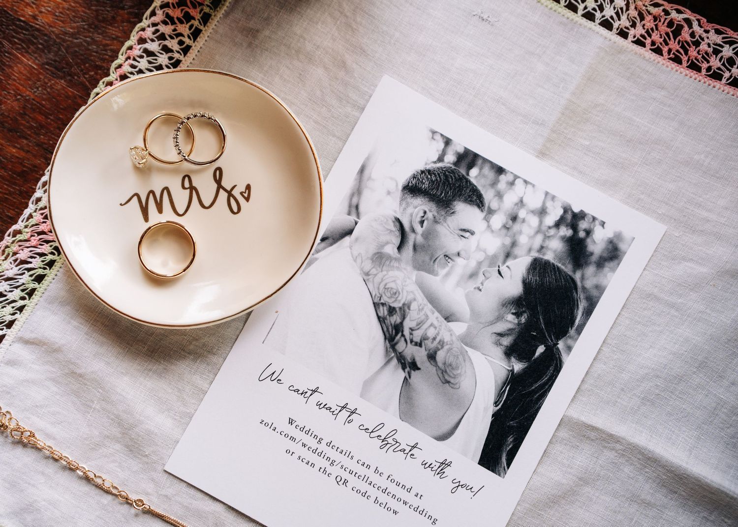 Romantic wedding details featuring ring dishes, black and white photos, and delicate decor arranged on white textiles.