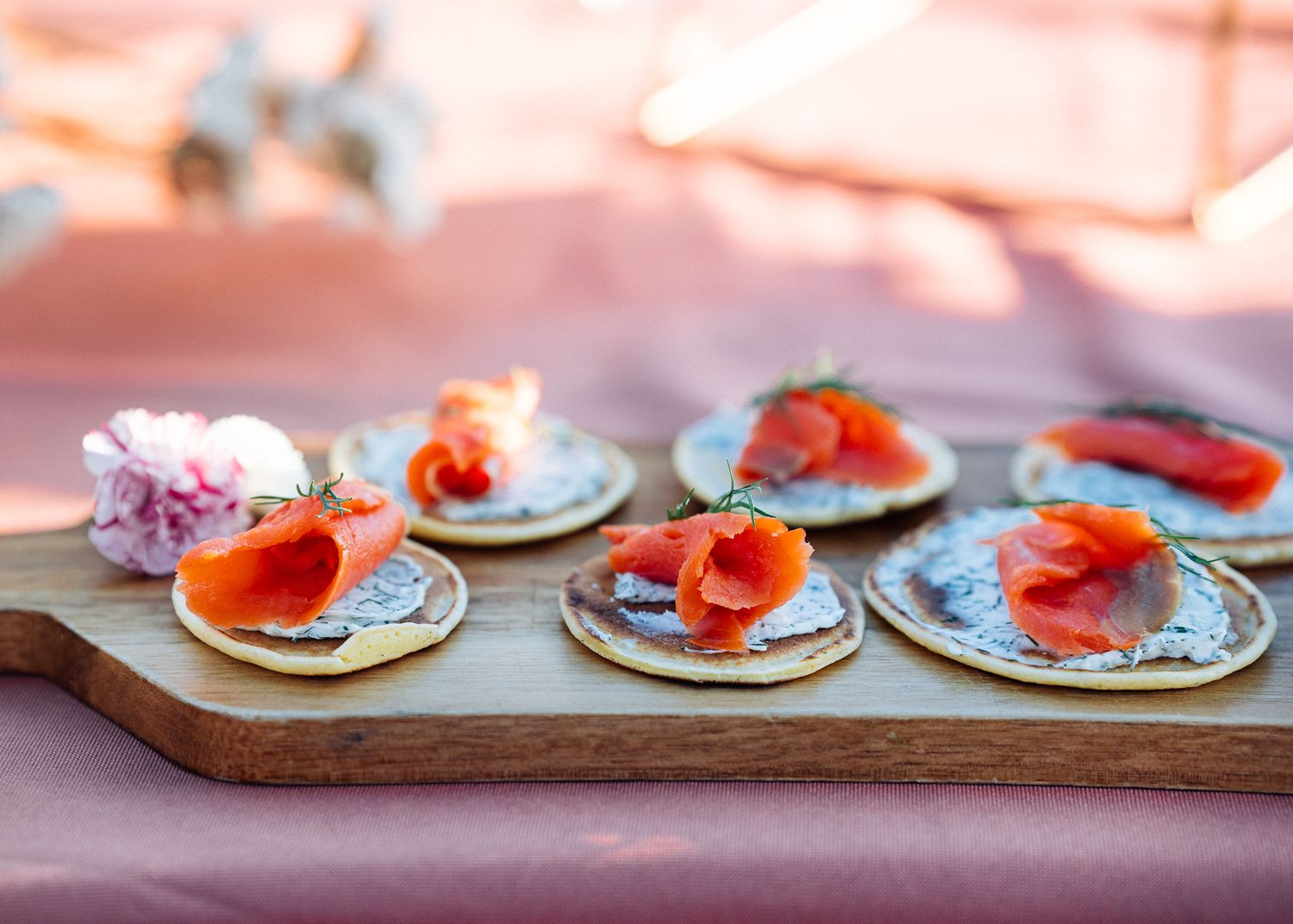 Small plates of smoked salmon appetizers with garnish served on a wooden board.