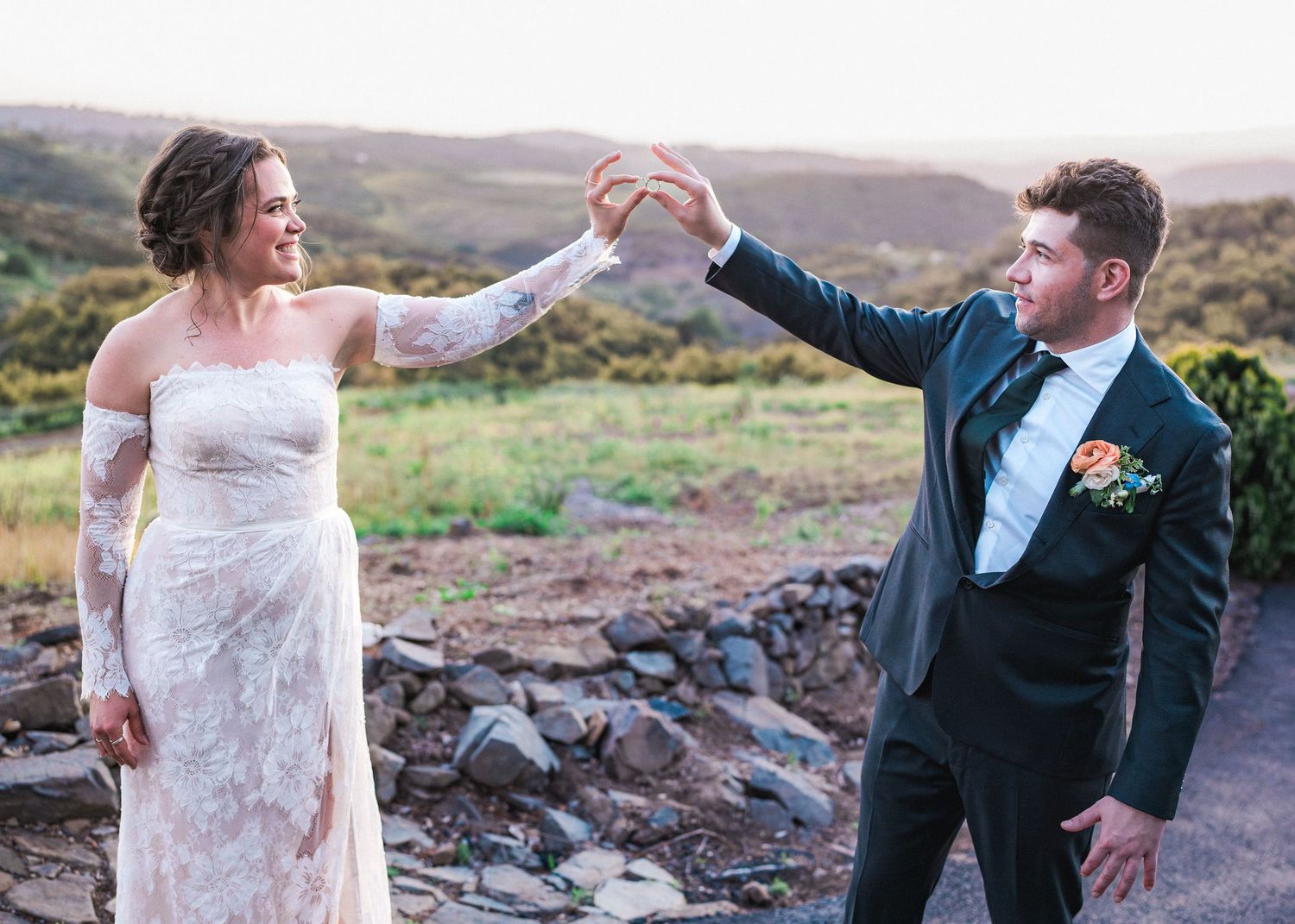 Wedding couple celebrating outdoors with joyful dance moves against rocky landscape.