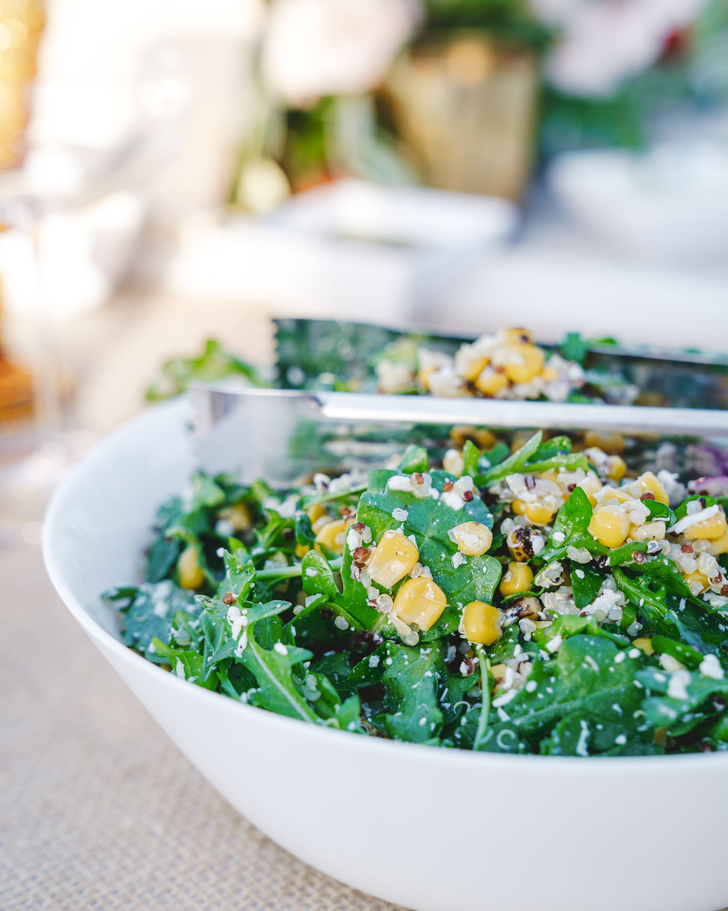 Fresh kale salad with corn, nuts and other toppings served in a white bowl.