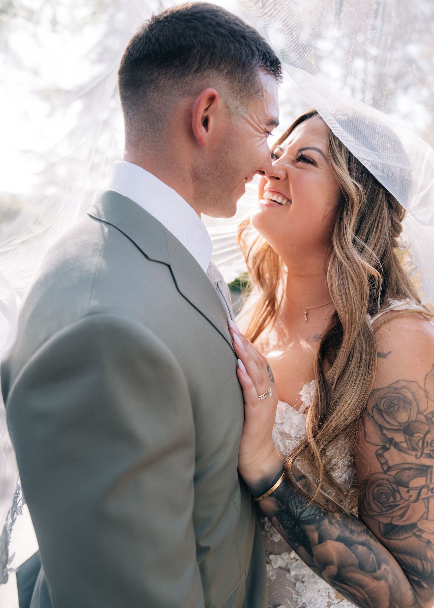 A romantic wedding portrait showing a couple in elegant attire sharing an intimate moment against a light background.