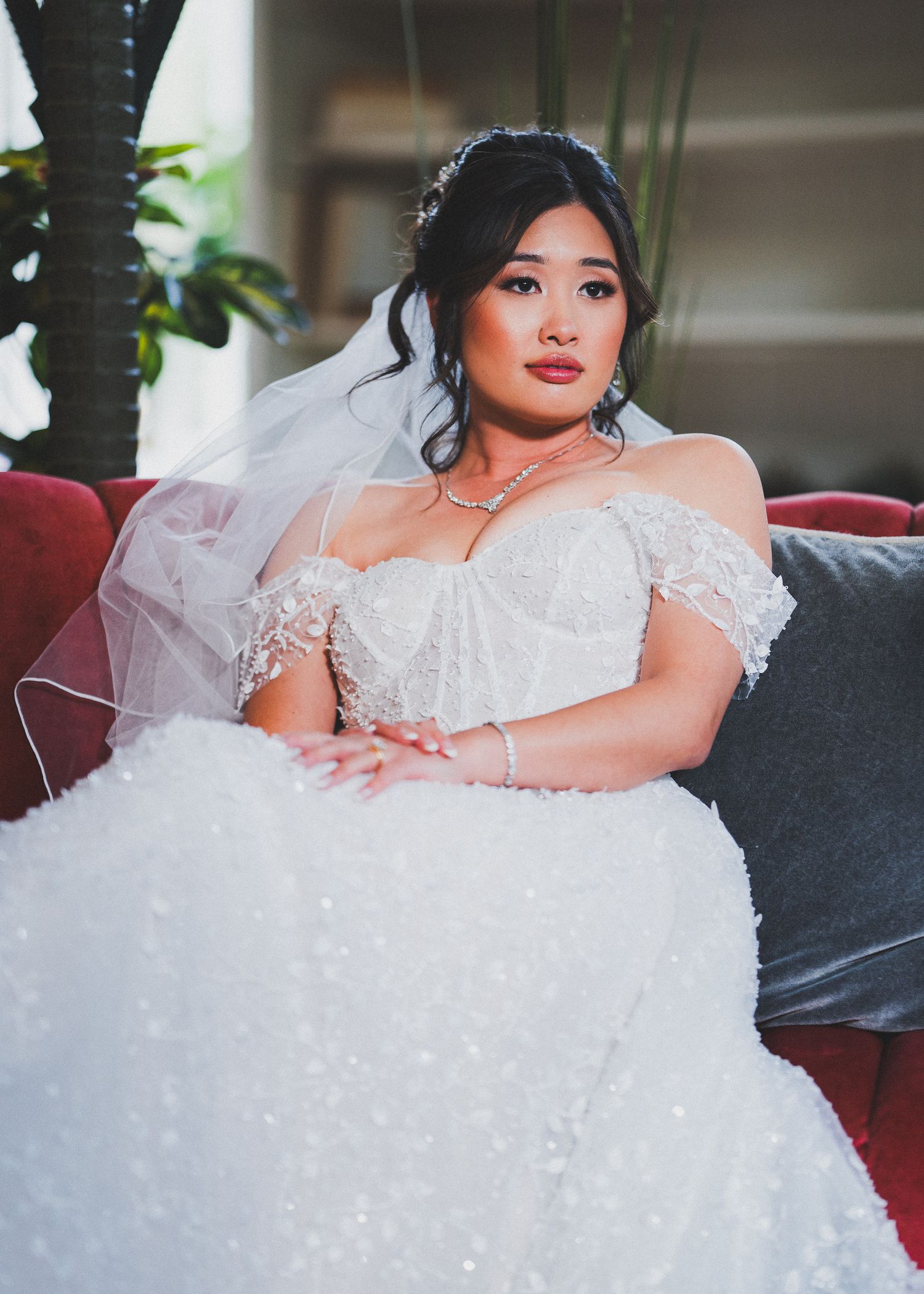 Elegant wedding gown with sparkly details displayed on grey couch.