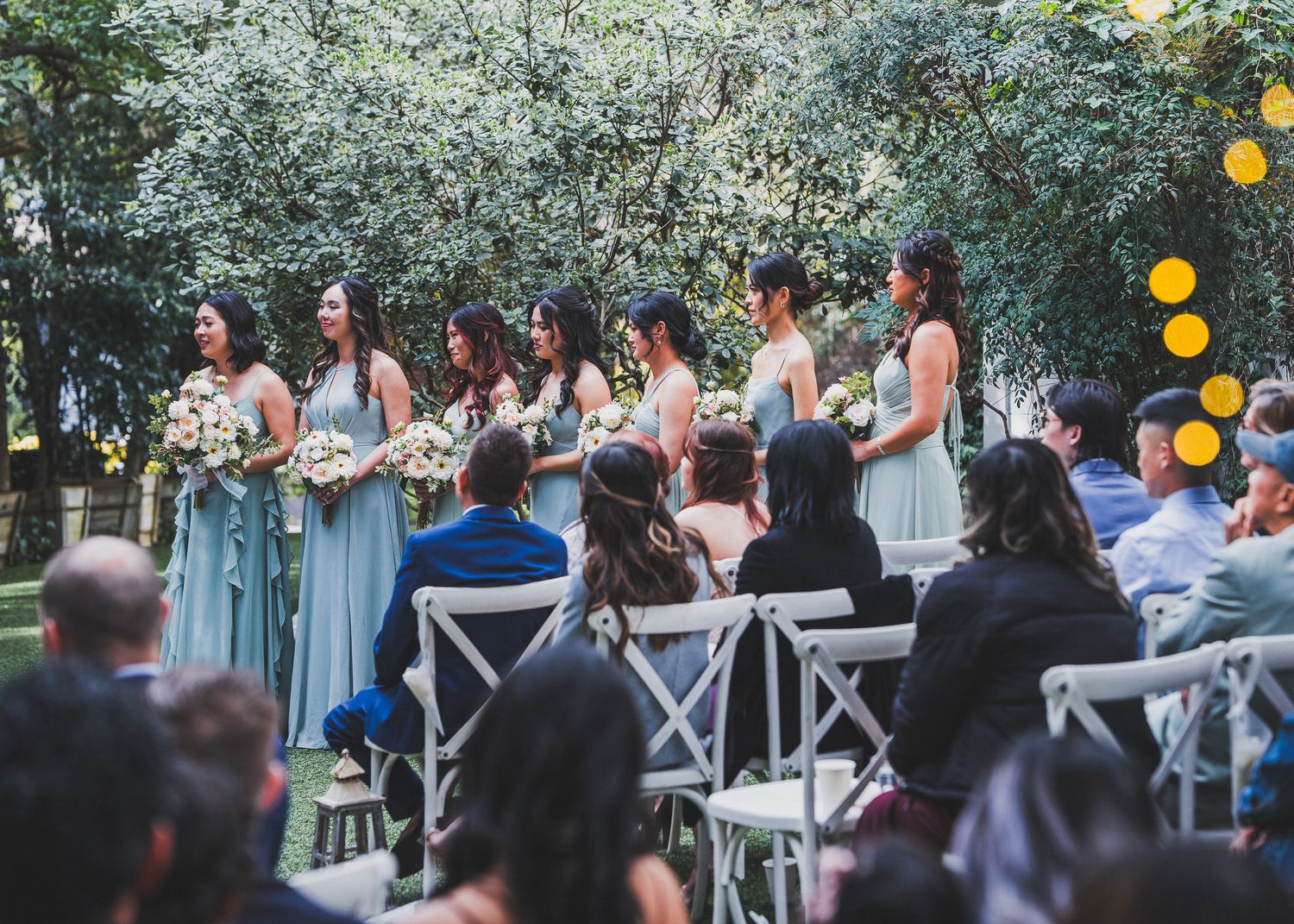 Outdoor wedding reception setup with string lights and white decor.