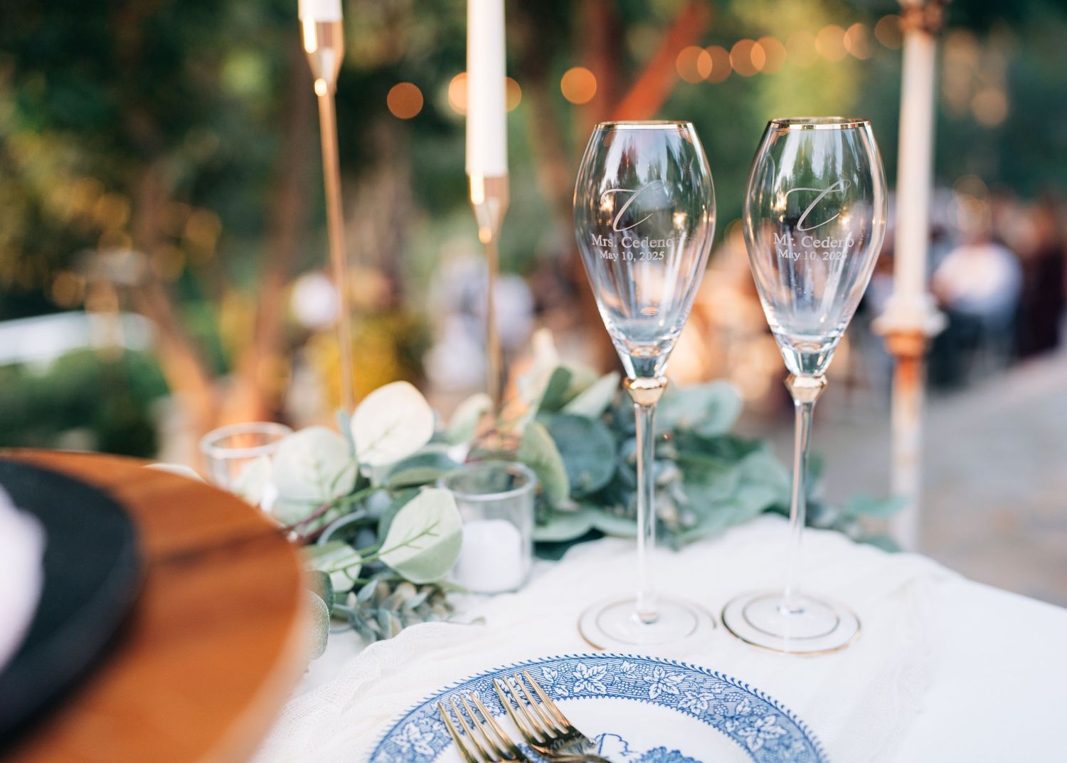 Elegant table settings with blue and white china plates, wine glasses, and greenery at a formal dinner event.